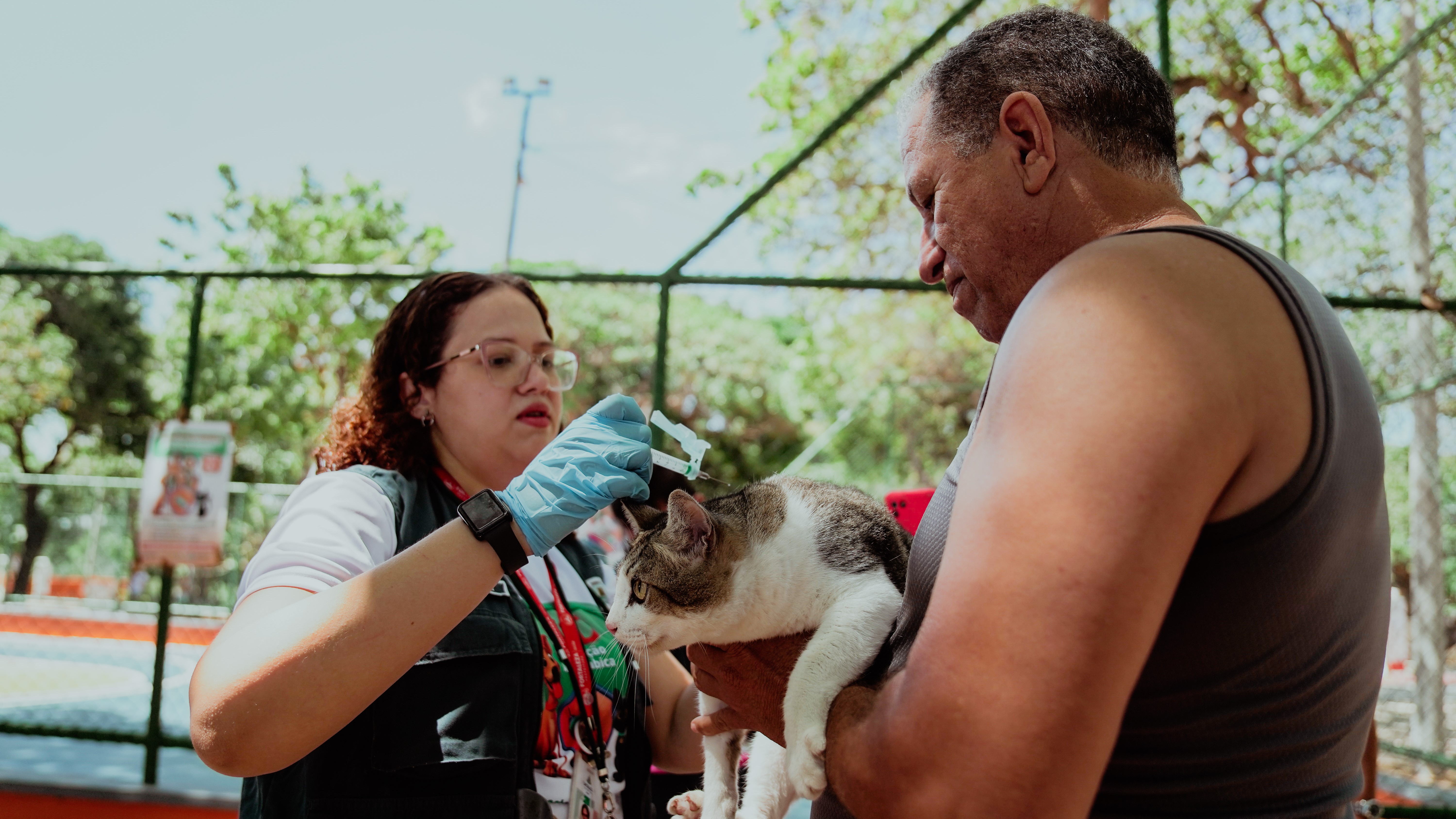 agente de saúde vacina um gato que está no colo do tutor
